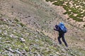 Side view of a woman tourist figure with a large backpack climbing steep rocky slope in Himalayas, Ladakh, India