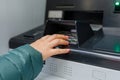 Side view of woman using ATM cash machine to enter the security PIN and retrieve withdrawal withdrawal money Royalty Free Stock Photo