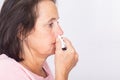 Side view of a woman using nasal spray.