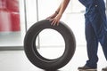 Side view. Woman walks with brand new wheel to the car. Conception of repair Royalty Free Stock Photo