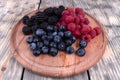 Composition of three types of summer berries laying on textured wooden plate Royalty Free Stock Photo