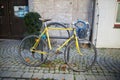 Side view of yellow bicycle locked onto a metal structure on cobblestone sidewalk Royalty Free Stock Photo