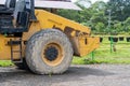 Side view of a yellow road roller that\'s on the stand by mode without the roll at a park