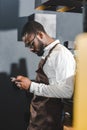 side view of young african american bartender using smartphone