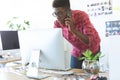 Graphic designer talking on mobile phone while working on computer at desk Royalty Free Stock Photo