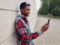Side view young african man using or taking selfie picture by phone on city street Royalty Free Stock Photo
