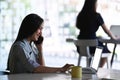 Young Asian businesswoman working with laptop computer and talking on mobile phone at modern office. Royalty Free Stock Photo