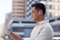 Side view of a young Asian man typing on his cellphone in the city Royalty Free Stock Photo