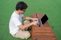 Side view of young Asian man using computer laptop at outdoors. Royalty Free Stock Photo