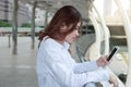 Side view of young Asian woman looking on mobile smart phone in her hands at building urban background. Royalty Free Stock Photo