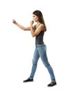 Side view of young attractive woman in gray sleeveless top and blue jeans posing with arms in figthing position isolated