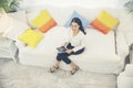 Side view of Young beautiful Asian woman look at the camera sitting on white sofa using tablet smartphone explore website. reading Royalty Free Stock Photo