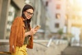 Side view of a young beautiful business woman using her smartphone, texting sms or chatting with friend while standing Royalty Free Stock Photo