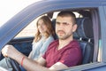 Side view of young beautiful couple has trip in car, look at camera, being in their automobile, enjoy high speed. Family cover Royalty Free Stock Photo