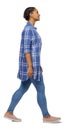 Side view of a young black girl walking in jeans and a checkered shirt