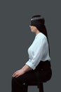 side view of young blindfolded woman sitting on chair