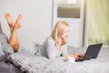 Pretty woman using laptop while having a cup of coffee on bed Royalty Free Stock Photo