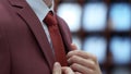 Side View of Young Business Man Fixing his Tie and red jacket Royalty Free Stock Photo
