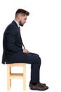 Side view of young businessman sitting on wooden chair Royalty Free Stock Photo