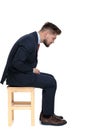 Side view of young businessman sitting on wooden chair Royalty Free Stock Photo