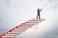 Side view of businessman with telescope on red book steps. Cloudy sky background with mock up place. Growth and education Royalty Free Stock Photo