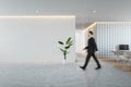 Side view of young businessman walking in modern concrete and wooden coworking office interior with empty mock up place on wall, Royalty Free Stock Photo