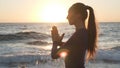 Side view of young caucasian girl practicing yoga at sunset seashore. Royalty Free Stock Photo