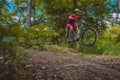 side view of young caucasian male jumping with a mountain bike over a jump on a singletrail. Epic ride with a modern mountain bike