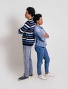 Side view of young couple with arms crossed standing back to back and ignoring over white background Royalty Free Stock Photo