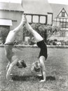 Side view of young couple doing handstands in yard