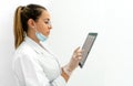 Side view of a young doctor using a tablet with the mask down in her clinic Royalty Free Stock Photo