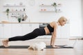 Pet owner holding High Plank while looking at laptop indoors