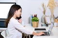 Young female entrepreneur working with laptop computer and talking on mobile phone at modern workplace. Royalty Free Stock Photo