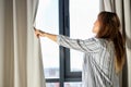 side view on young female opening the curtains in the morning Royalty Free Stock Photo
