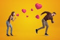 Side view of young girl following with her eyes young man who`s running away being chased by cute valentine hearts that