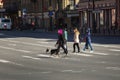 Side view of a young girl with pink hair and a bulldog on a leash walking along a pedestrian crossing on Nevsky Prospekt