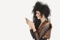Side view of young Goth woman with teased hair texting on mobile phone over gray background Royalty Free Stock Photo