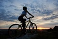 Side view of young lady cycling in mountains with an evening landscape Royalty Free Stock Photo