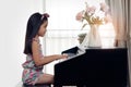 Side view of young little Asian cute girl playing electronic piano at home.