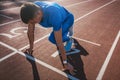 Side view of young male athlete at starting block on running track. Caucasian sprinter man in starting position for running to Royalty Free Stock Photo