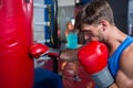 Side view of young male boxer punching red bag Royalty Free Stock Photo