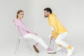 side view of young male and female models in pink and yellow hoodies sitting on chairs Royalty Free Stock Photo