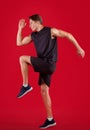 Side view of young male sprinter running, exercising on red studio background Royalty Free Stock Photo