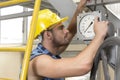 Side view of young male worker checking pressure gauge in industry