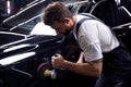 Side view on young man auto mechanic worker polishing car at automobile repair and renew service station shop Royalty Free Stock Photo