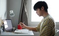 Side view young man college or university student using laptop computer and doing homework at home Royalty Free Stock Photo