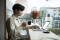 Young man drinking coffee and using computer laptop in bright office room. Royalty Free Stock Photo