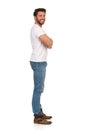 Side View Of Young Man In Jeans And White T-shirt Is Standing With Arms Crossed, Looking At Camera Royalty Free Stock Photo