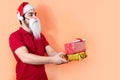 Side view of a young man with Santa Claus hat and white beard, offering presents Royalty Free Stock Photo