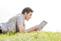 Side view of young man using digital tablet while lying on grass against clear sky Royalty Free Stock Photo